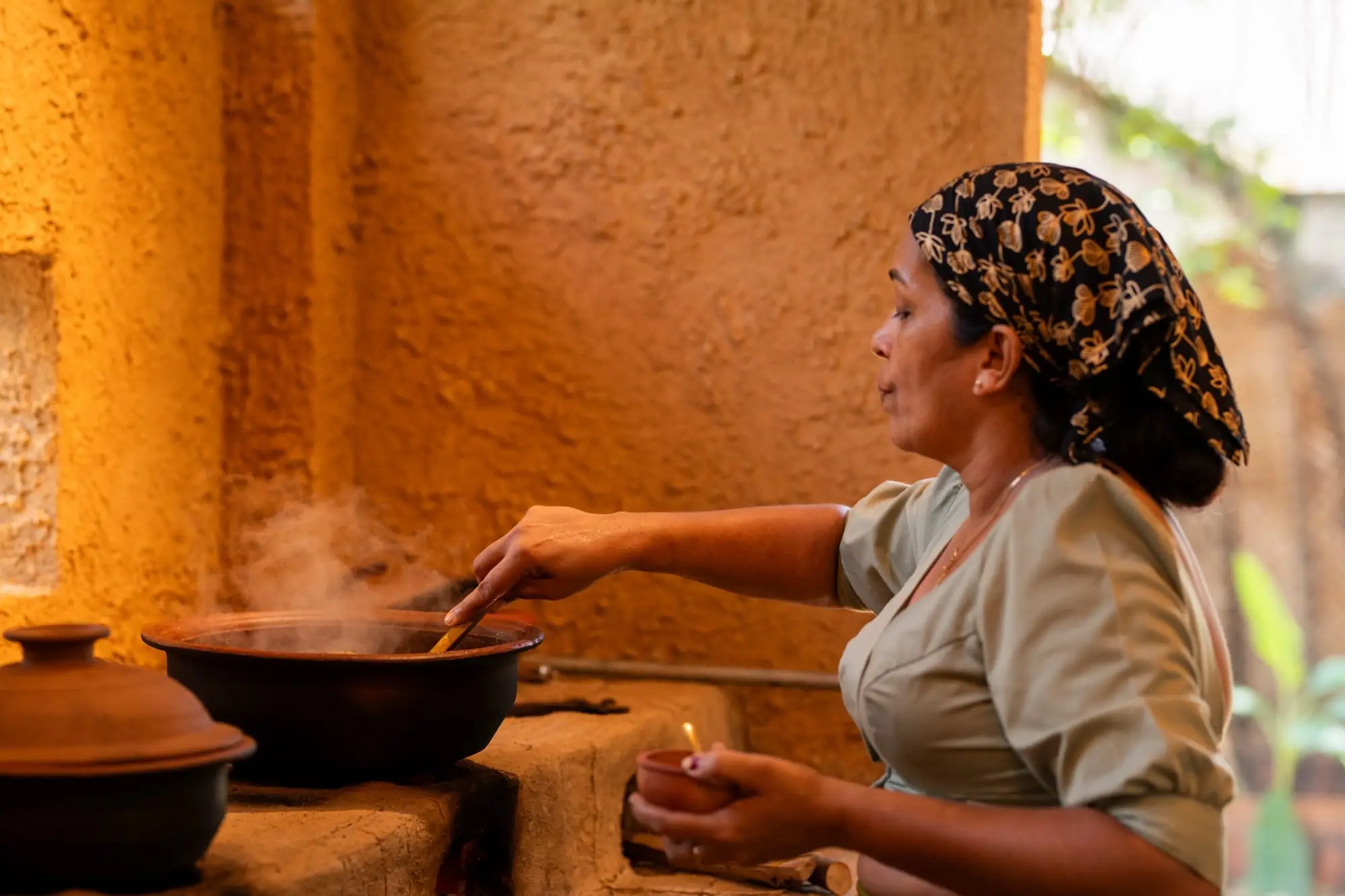 A cook stirring a clay pot on the wood-fired hearth at Karma Kitchen