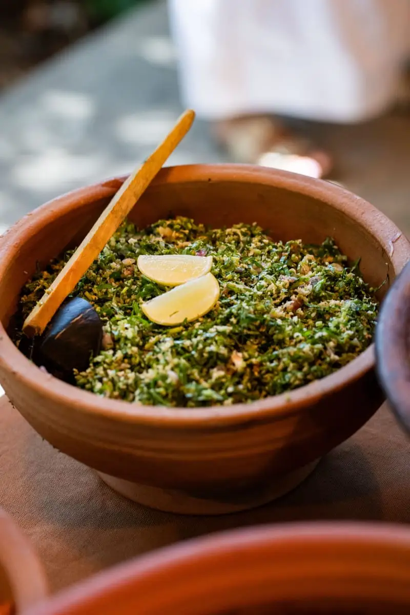 Chopped greens with a slice of lime in a clay pot