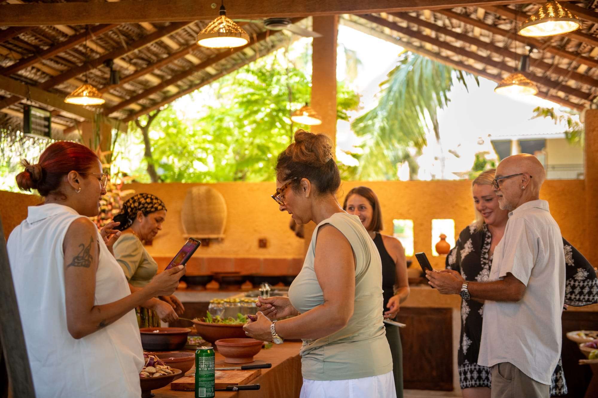 Guests chatting at the kitchen counters under the thatched roof