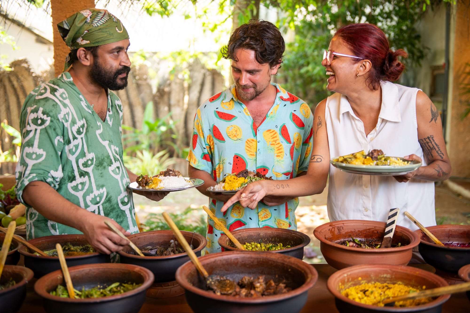 Hosts laughing as they serve curries from a row of clay pots