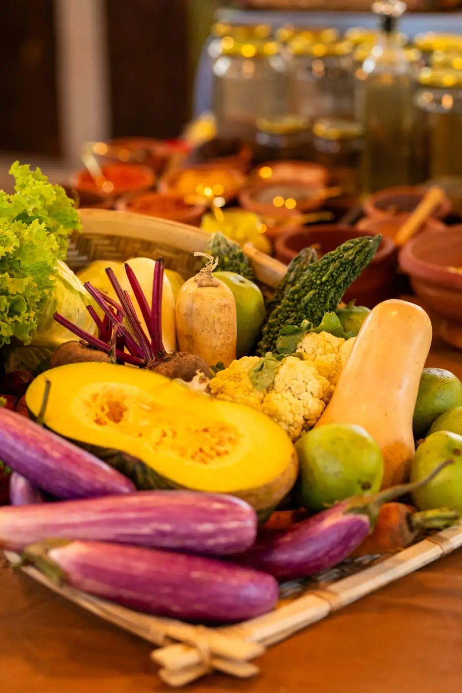 Pumpkin, aubergine, gourds and greens laid out on a woven tray